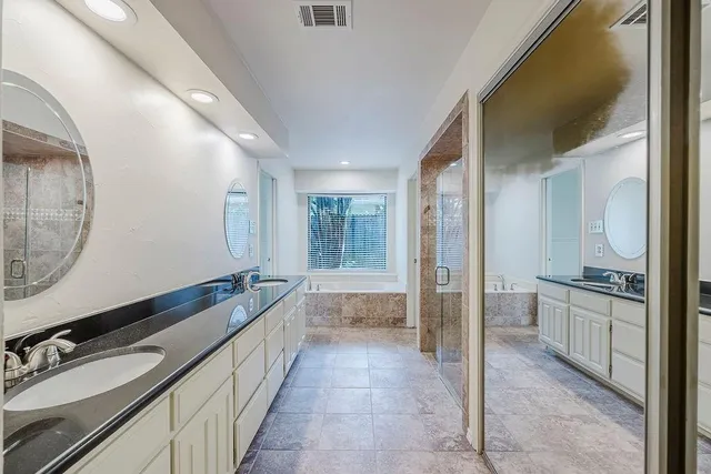 a spacious bathroom with a double vanity sink a mirror and a shower