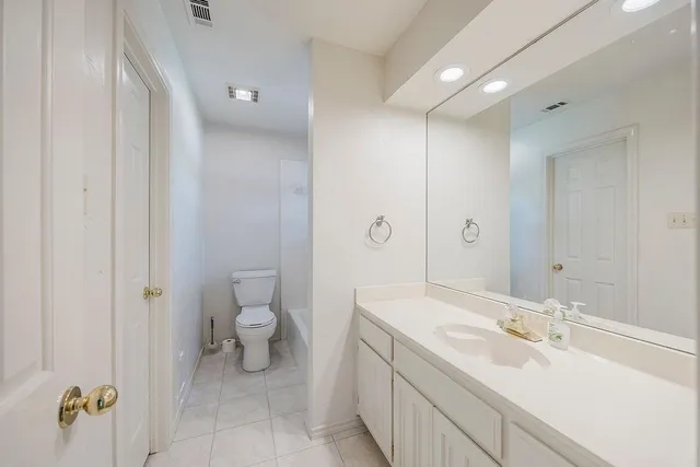 a spacious bathroom with a granite countertop sink a toilet and a mirror