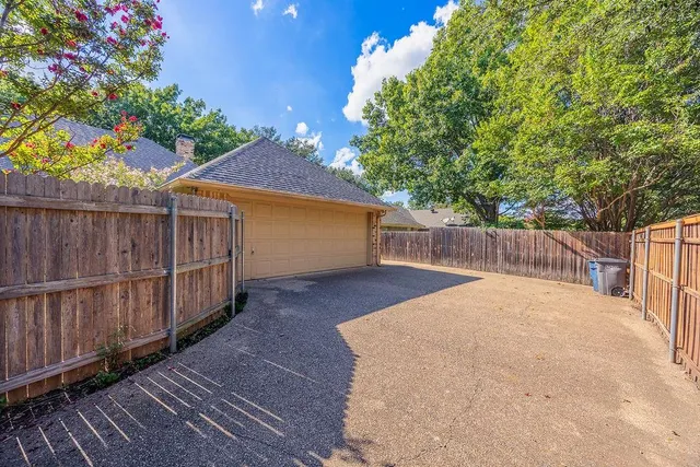 a view of a backyard with wooden fence and large trees