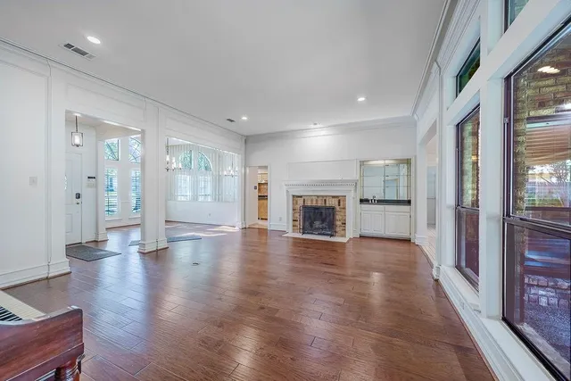 a view of an empty room with wooden floor and a fireplace