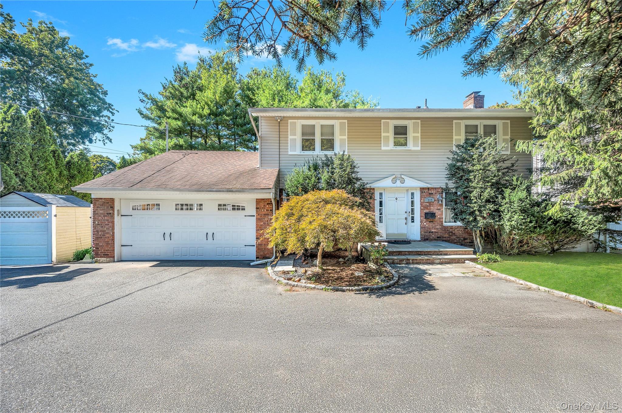 257 Berry Hill Road Syosset, NY 11791 - Photo 1 of 1 View of front of home with brick siding, a chimney, driveway, and an attached garage