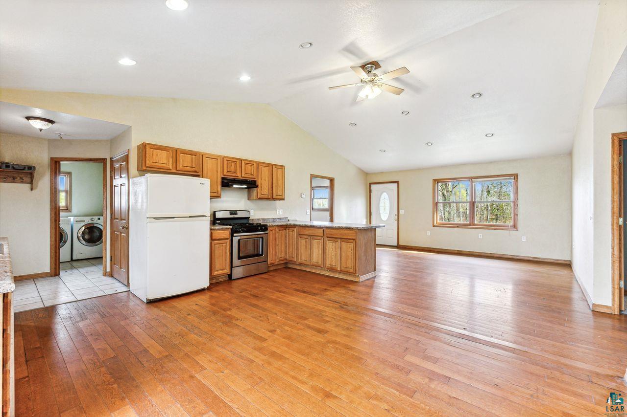 4503 Snooky Road South Range, WI 54874 - Photo 6 of 21 Kitchen with kitchen peninsula, stainless steel gas range oven, independent washer and dryer, light hardwood / wood-style floors, and white fridge