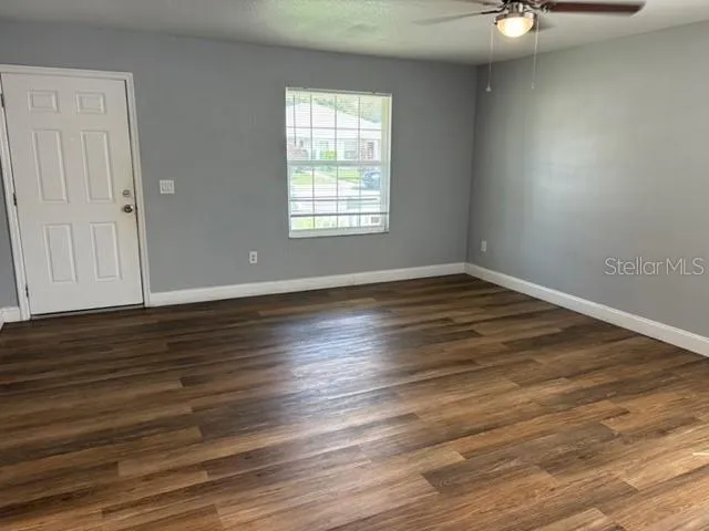 an empty room with wooden floor cabinet and windows