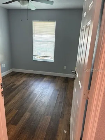 a view of an empty room with wooden floor and a window