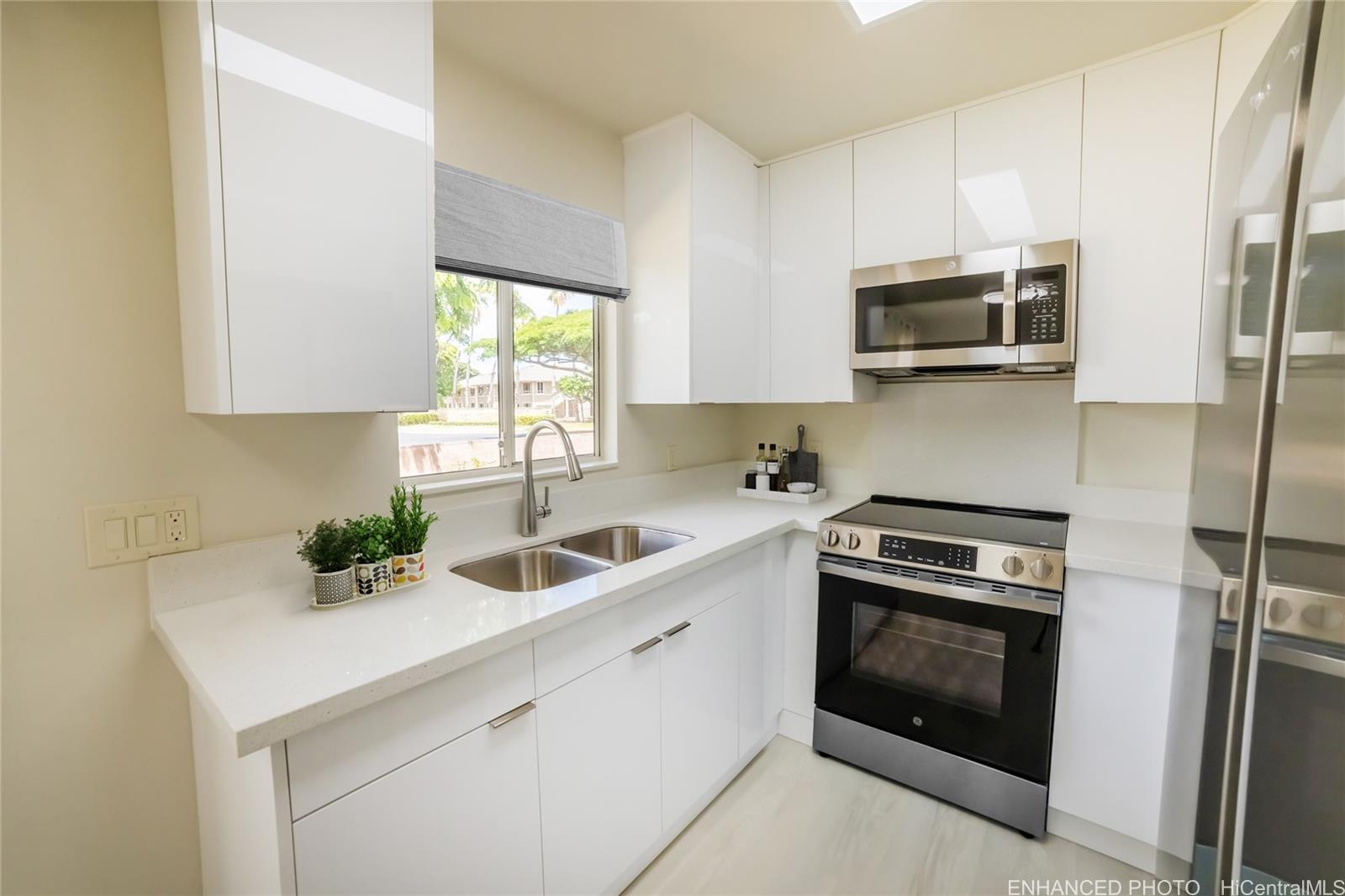 91-1147 Kamaaha Loop, Unit 6F Kapolei, HI 96707 - Photo 8 of 25 a kitchen with stainless steel appliances a sink a stove a microwave and cabinets