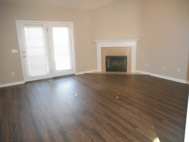 an empty room with wooden floor fireplace and windows