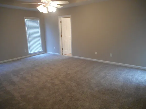 an empty room with a chandelier fan and windows
