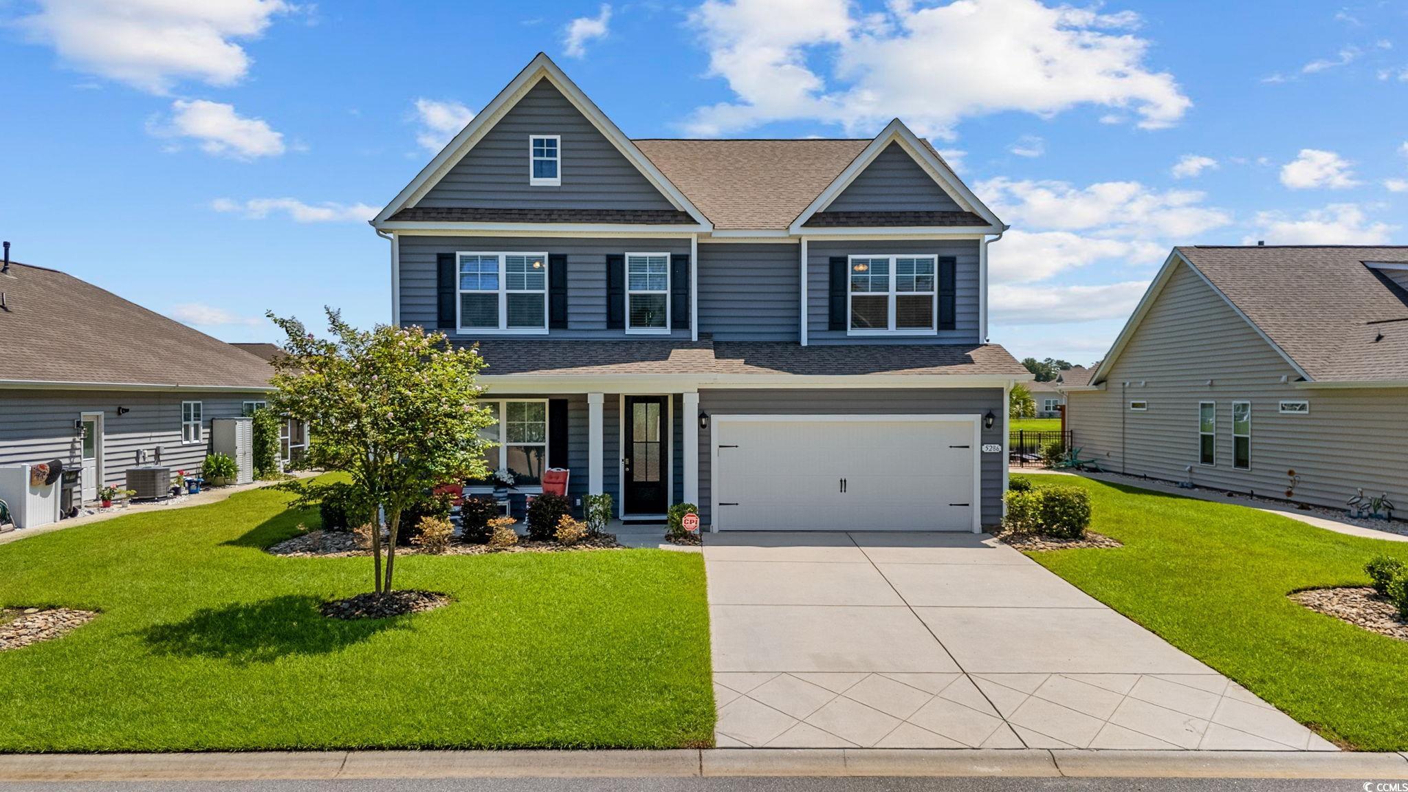 Craftsman-style home featuring an attached garage, a front lawn, a shingled roof, and concrete driveway