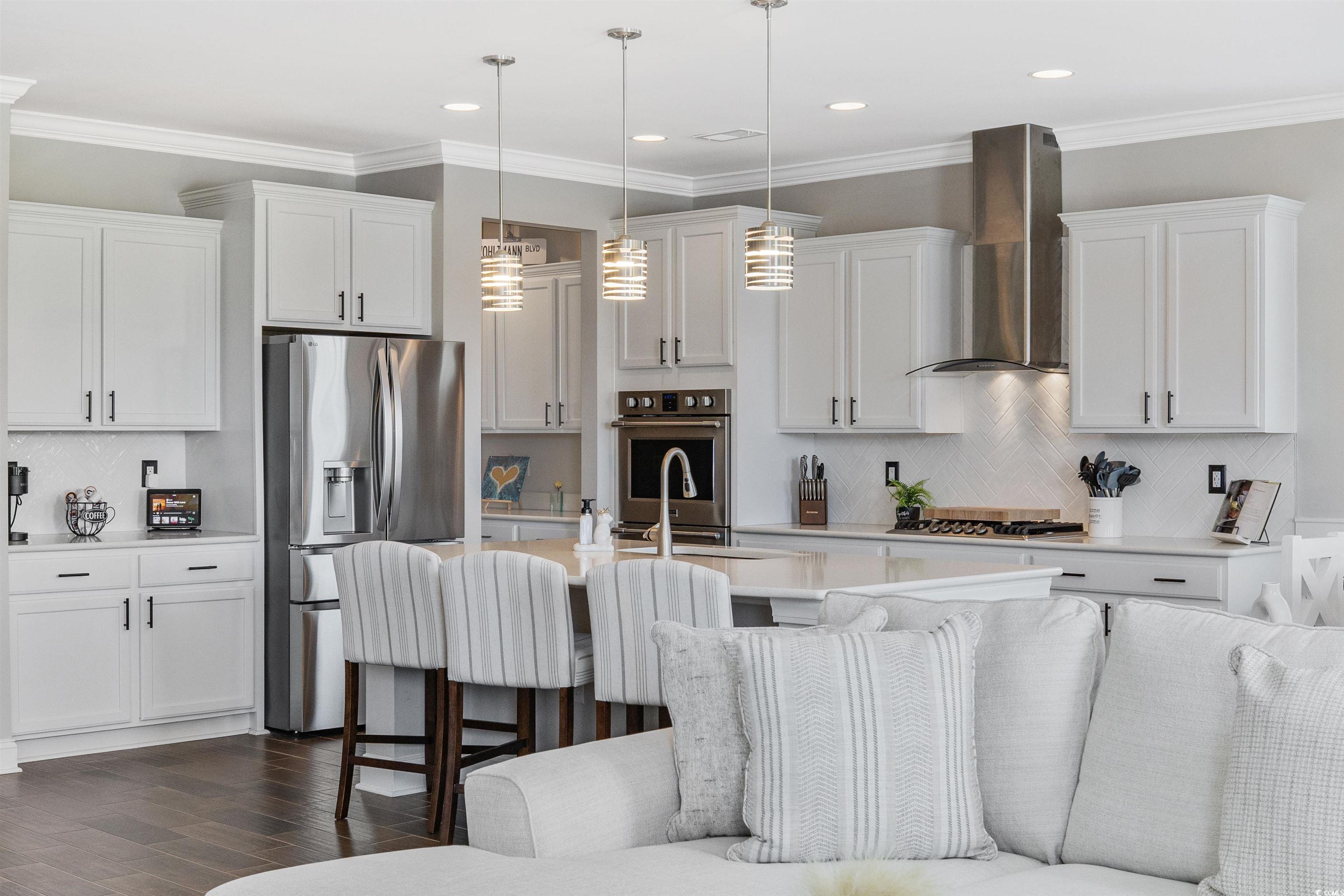5286 Stockyard Loop Myrtle Beach, SC 29588 - Photo 14 of 40 Kitchen featuring crown molding, stainless steel appliances, white cabinetry, backsplash, and wall chimney range hood