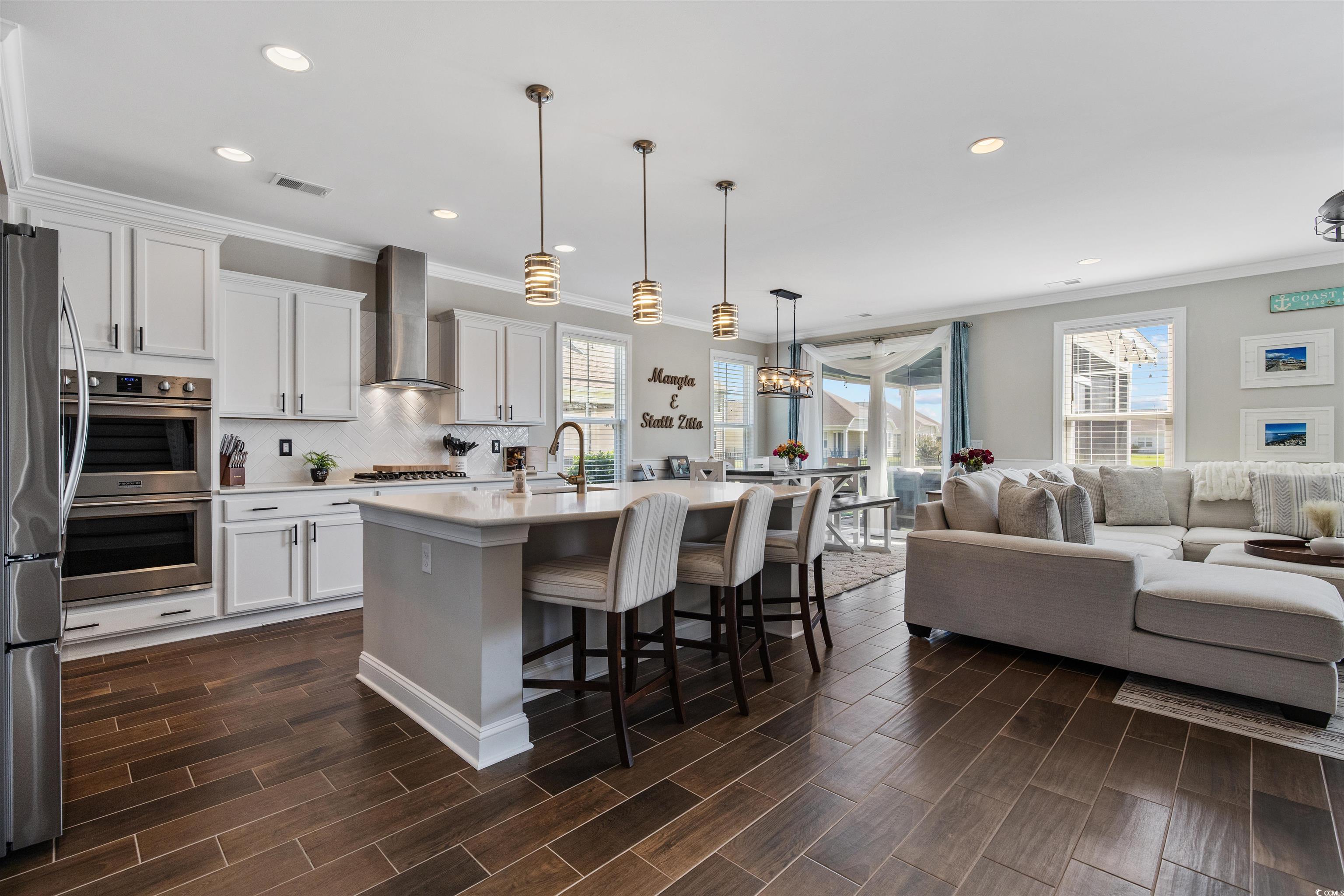 5286 Stockyard Loop Myrtle Beach, SC 29588 - Photo 16 of 40 Kitchen with a kitchen bar, crown molding, a center island with sink, white cabinets, and decorative light fixtures