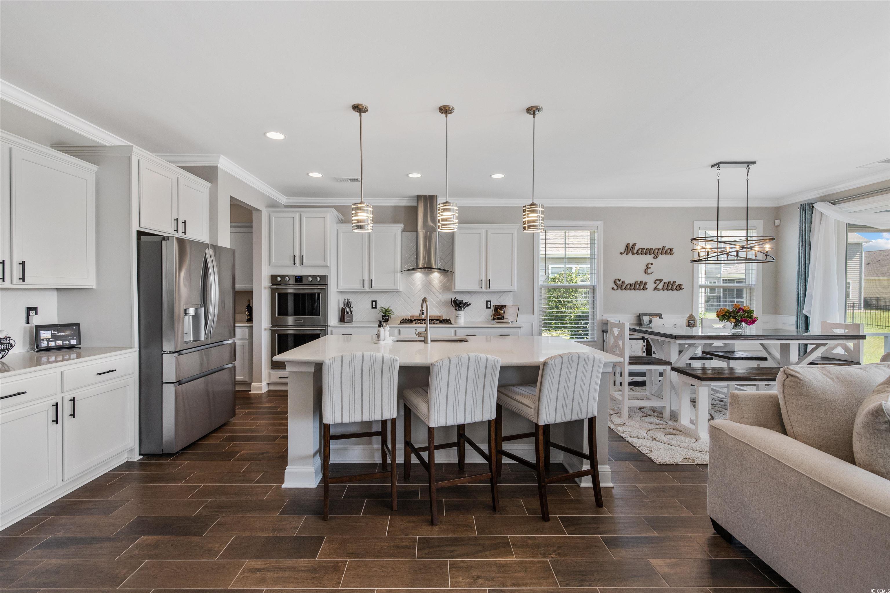 5286 Stockyard Loop Myrtle Beach, SC 29588 - Photo 18 of 40 Kitchen featuring ornamental molding, stainless steel appliances, hanging light fixtures, white cabinets, and a kitchen breakfast bar