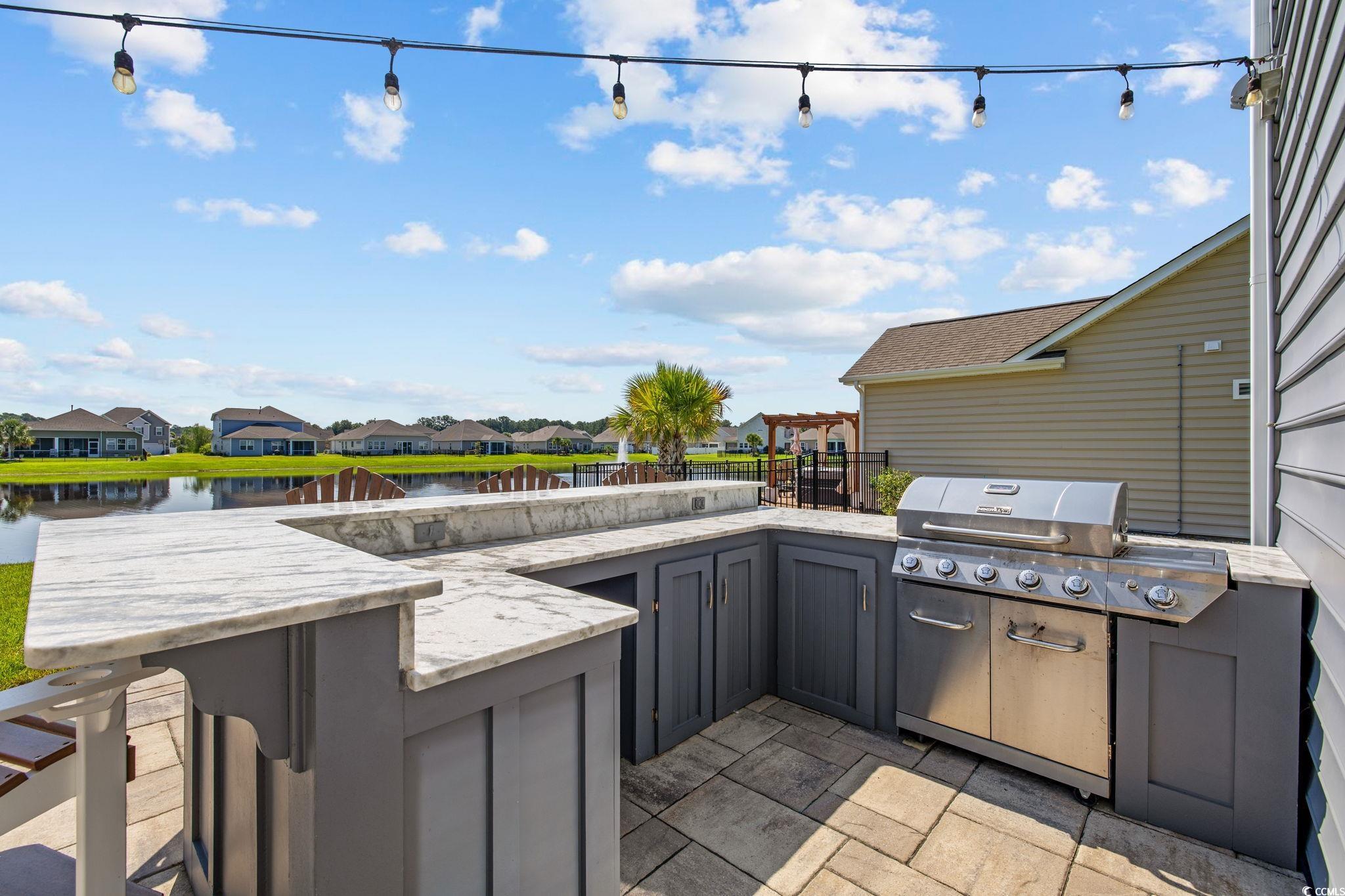 View of patio / terrace featuring an outdoor kitchen, a residential view, and a water view