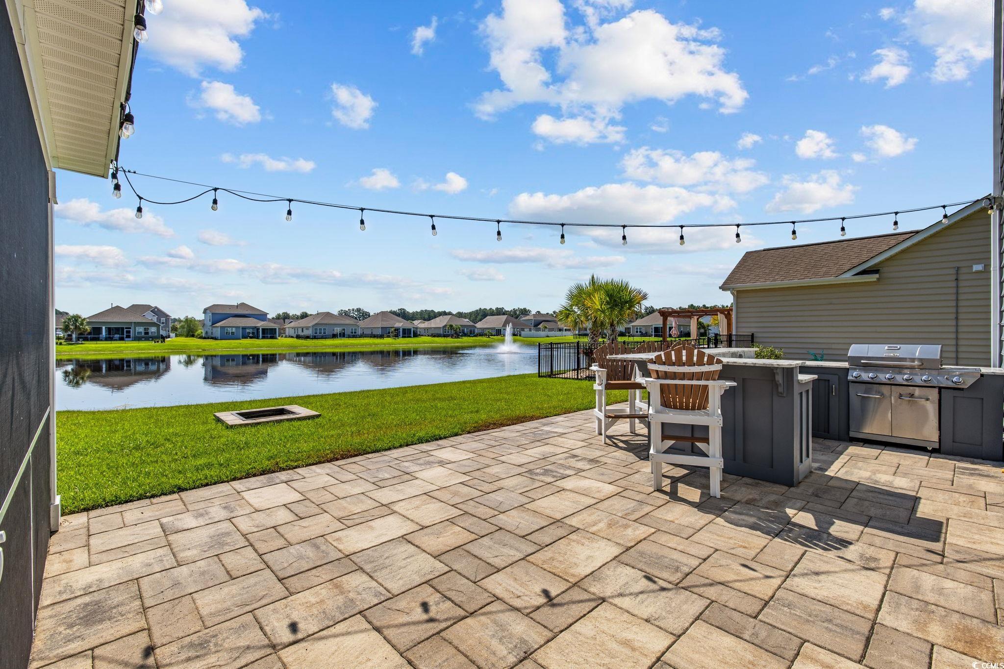 View of patio with a water view, an outdoor kitchen, and a residential view