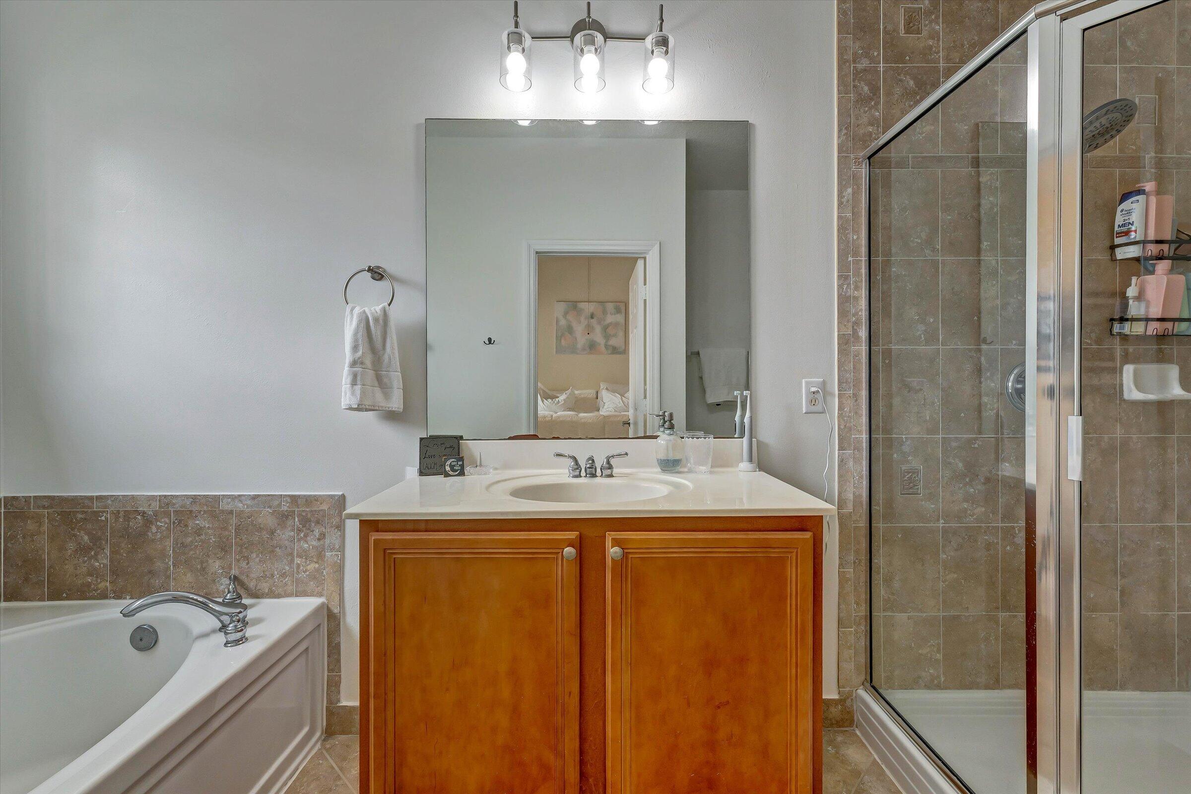 115 Pond Apple Lane, Unit 105 Jupiter, FL 33458 - Photo 31 of 38 a bathroom with a granite countertop sink a large mirror and a bathtub