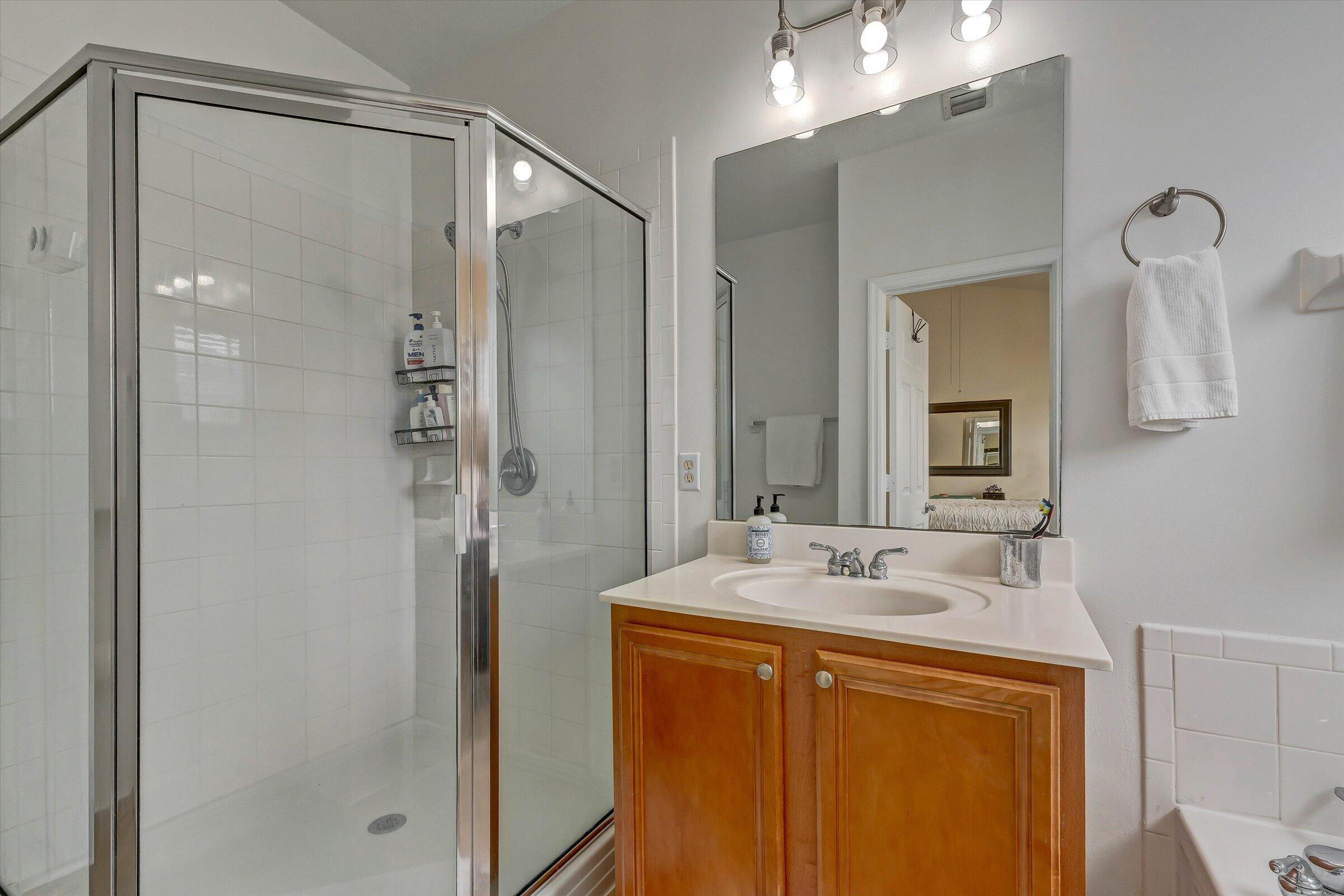 115 Pond Apple Lane, Unit 105 Jupiter, FL 33458 - Photo 32 of 38 a bathroom with a shower sink vanity and mirror