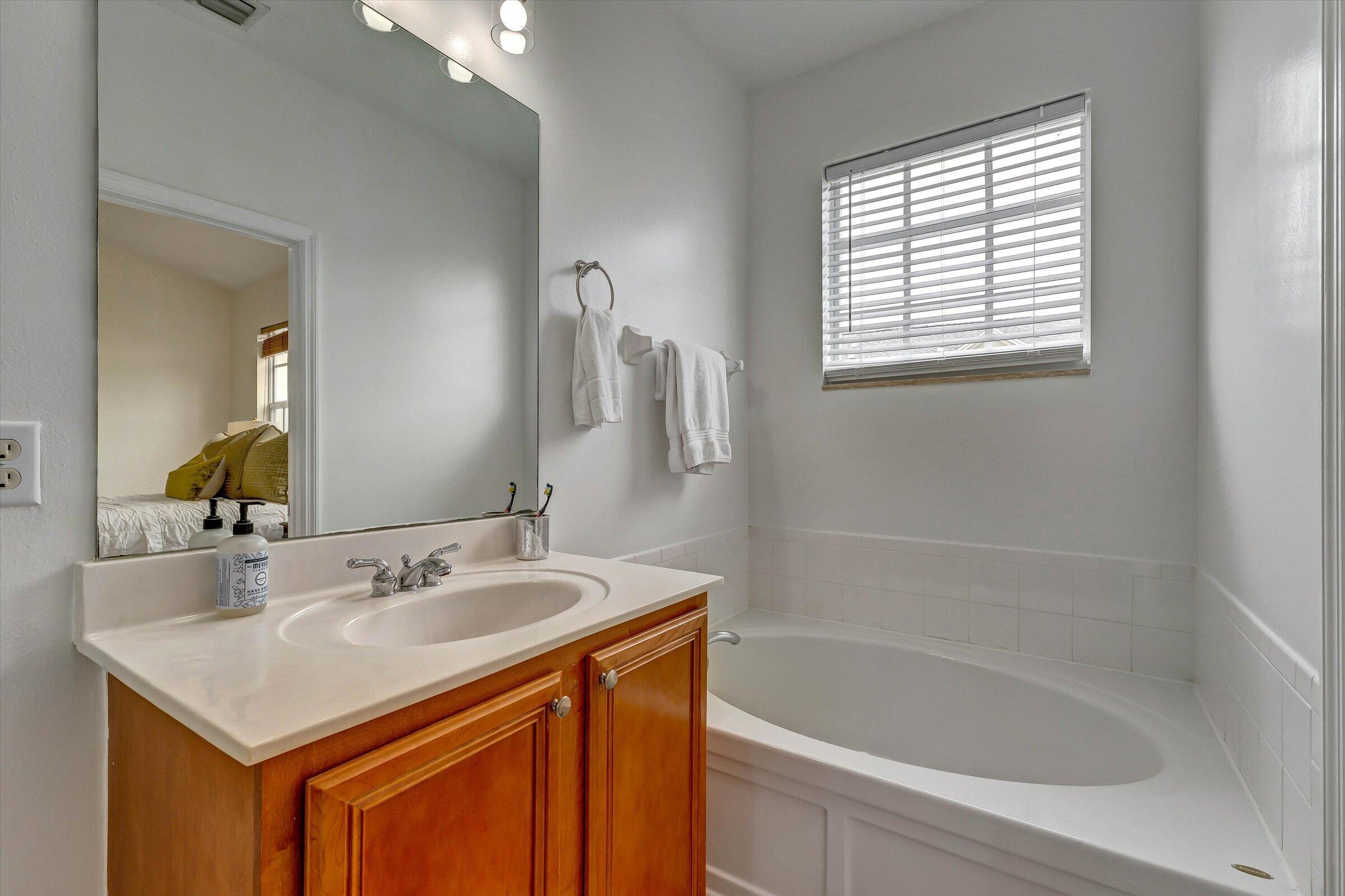 115 Pond Apple Lane, Unit 105 Jupiter, FL 33458 - Photo 33 of 38 a bathroom with a sink a bathtub and a mirror