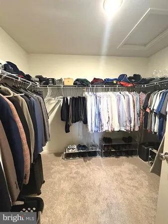 a view of walk in closet with clothes and shoes