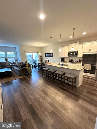 a large kitchen with stainless steel appliances a stove a refrigerator a kitchen island a stove and a wooden floors