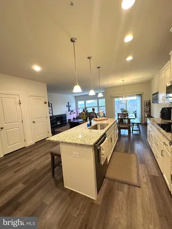a large kitchen with kitchen island a stove a sink a center island and wooden floor