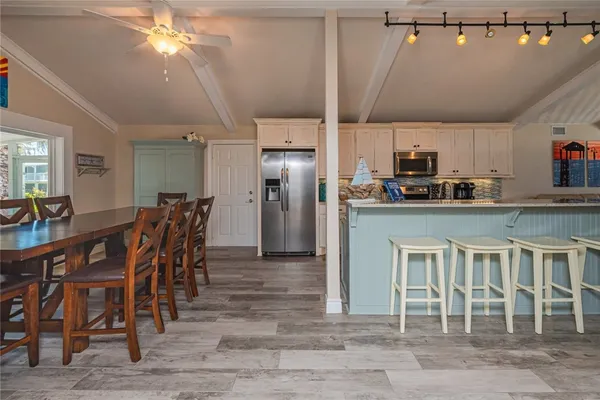 a dining area with stainless steel appliances kitchen island granite countertop a dining table chairs and granite counter tops