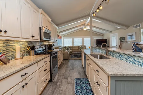 a kitchen with granite countertop a sink a counter space cabinets and appliances