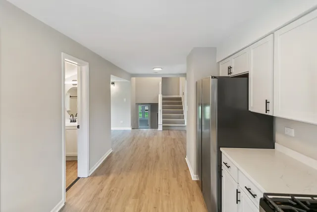 a view of a kitchen with a stove top oven a refrigerator and wooden floor