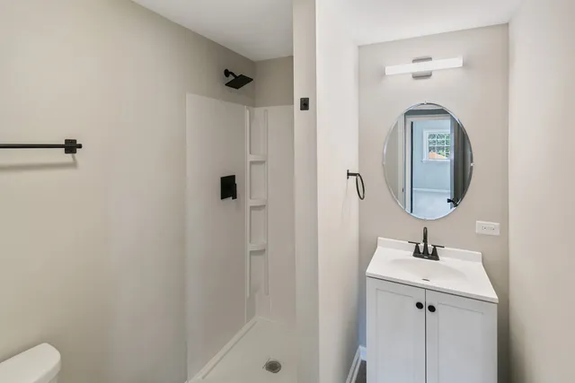 a bathroom with a toilet a sink a mirror and vanity