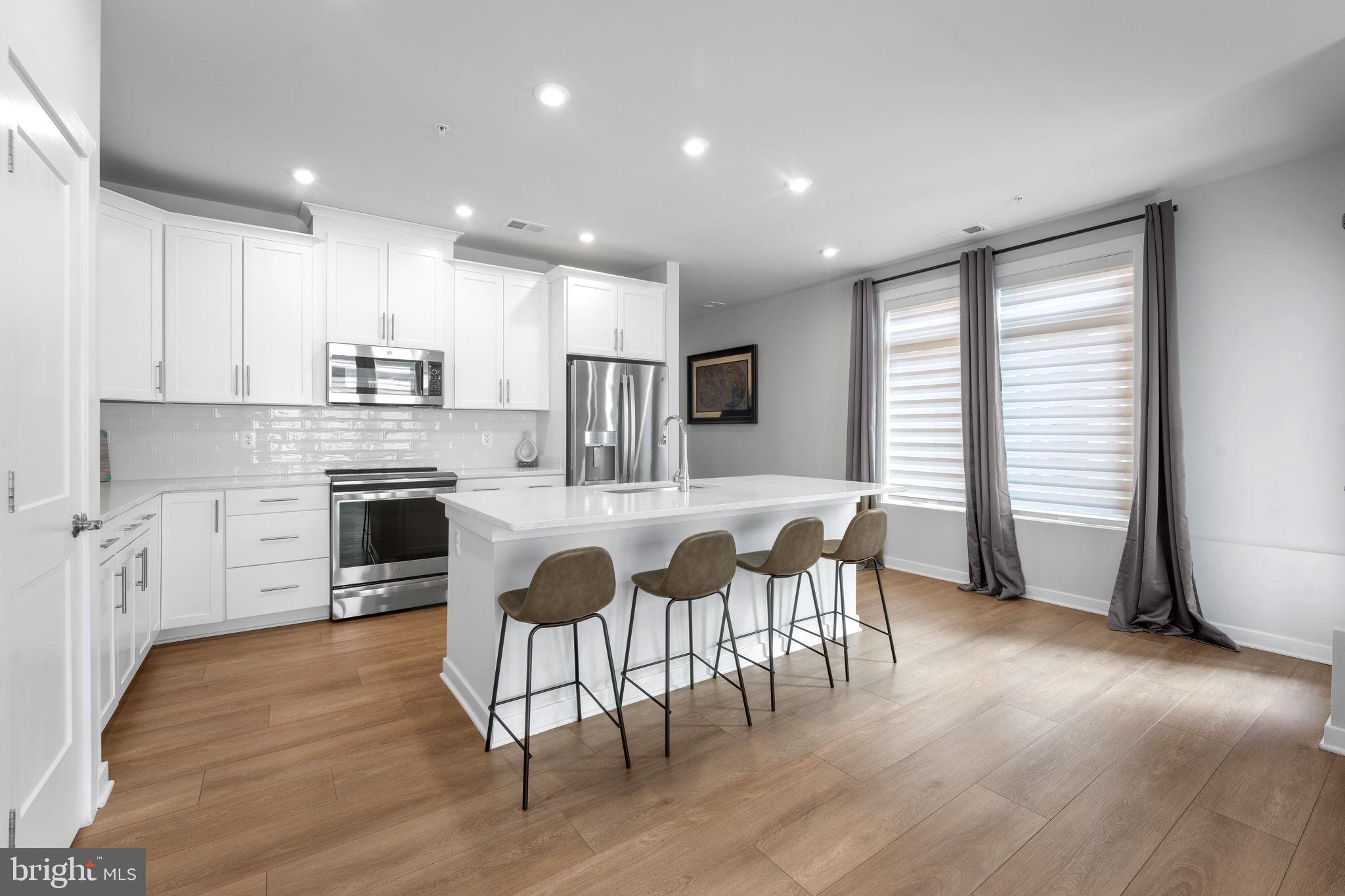 1669 Bandit Loop, Unit 101A Reston, VA 20190 - Photo 11 of 35 a large kitchen with cabinets chairs and wooden floor