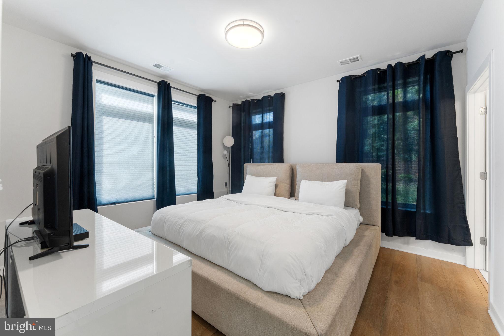 1669 Bandit Loop, Unit 101A Reston, VA 20190 - Photo 24 of 35 a bedroom with a large bed and a flat tv screen