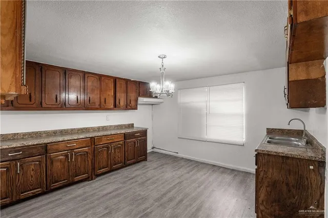 a kitchen with stainless steel appliances granite countertop wooden cabinets a stove top oven a sink and dishwasher with wooden floor