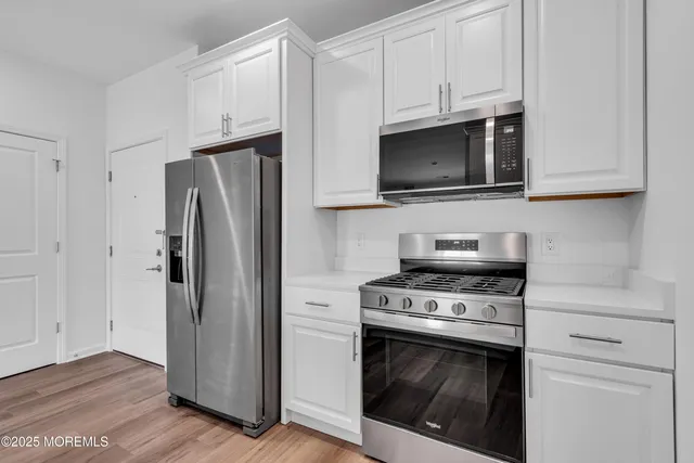 a kitchen with cabinets stainless steel appliances and a wooden floor