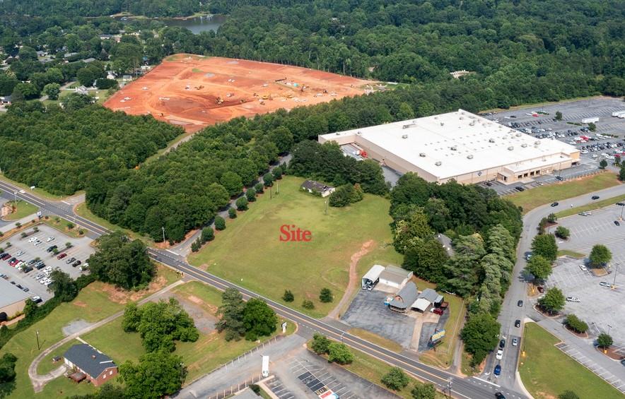 222 Brown Road Anderson, SC 29621 - Photo 3 of 12 A spacious land plot primed for development, surrounded by mature trees and adjacent to a substantial commercial building.