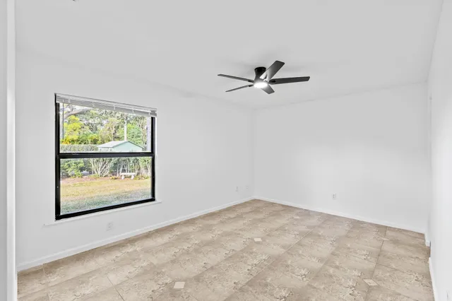 an empty room with a ceiling fan and window