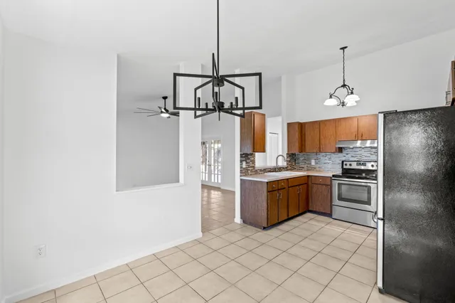 a view of an empty room with window and chandelier fan