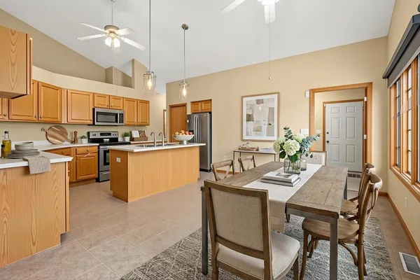 a view of kitchen with stainless steel appliances granite countertop a stove top oven a refrigerator a sink dishwasher with a dining table and chairs