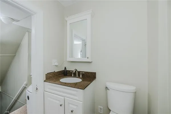 a bathroom with a granite countertop sink and a toilet