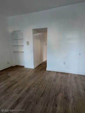 a view of an empty room with wooden floor and closet