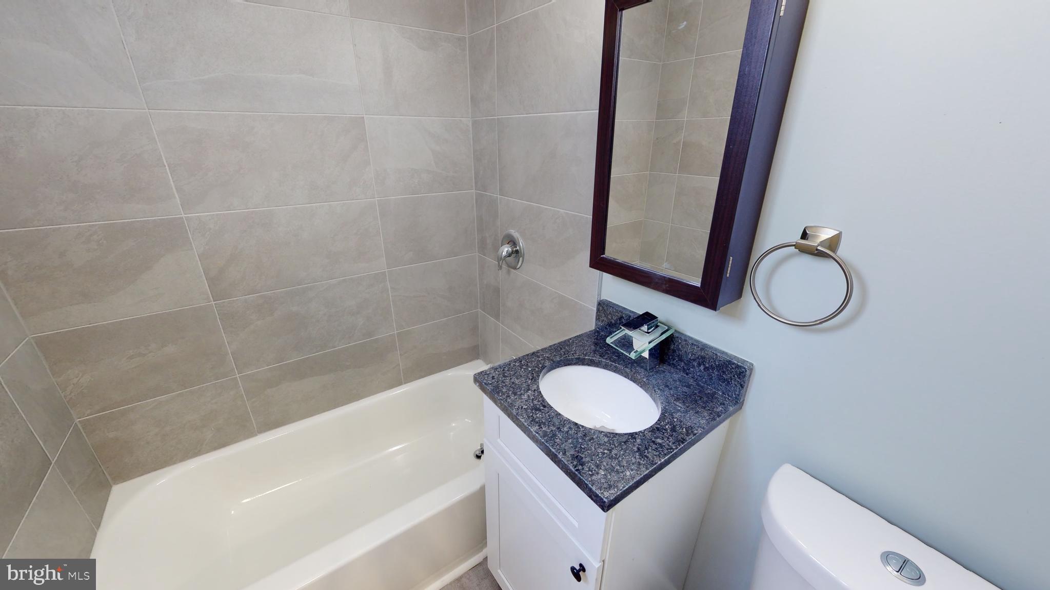 910 Gateway Boulevard, Unit C2 Westville, NJ 08093 - Photo 4 of 11 a bathroom with a granite countertop sink toilet and a bathtub