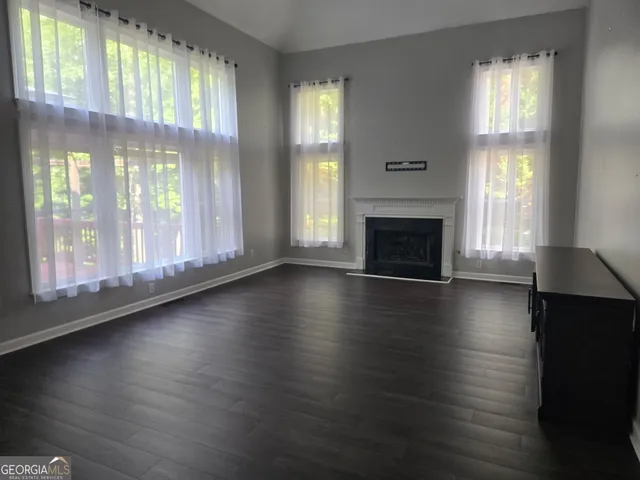 an empty room with wooden floor fireplace and windows