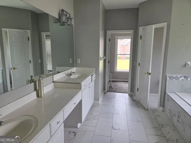 a spacious bathroom with a granite countertop sink a toilet a mirror and shower