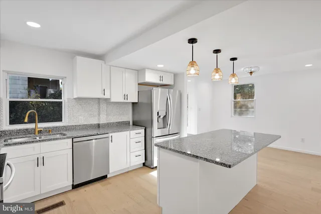 a kitchen with stainless steel appliances granite countertop a sink a stove and a refrigerator