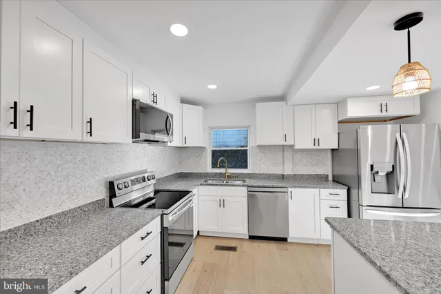 a kitchen with stainless steel appliances granite countertop a sink a stove and a refrigerator