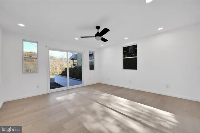 a view of an empty room with kitchen and window