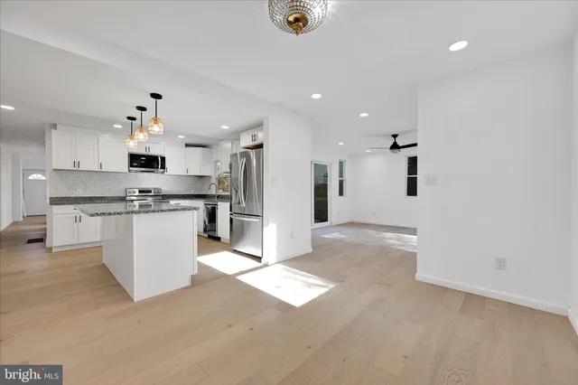 a view of kitchen with kitchen island white cabinets and stainless steel appliances