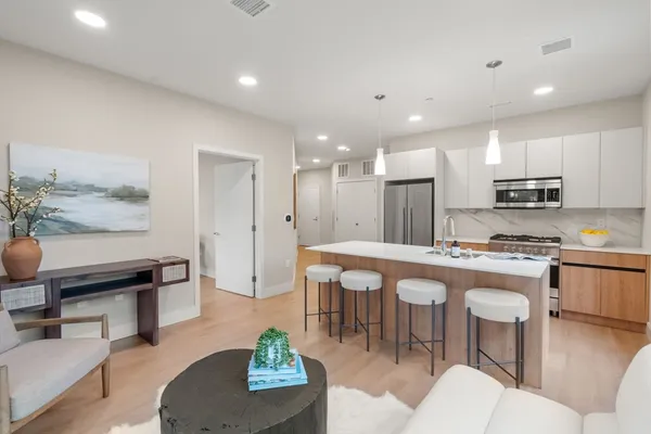 a kitchen with stainless steel appliances granite countertop a stove a sink a dining table and chairs with wooden floor