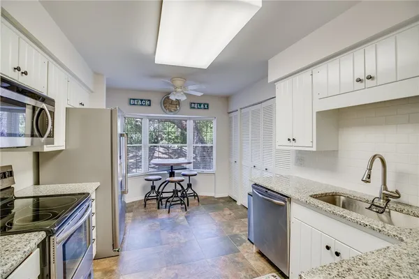 a kitchen with granite countertop a sink stove and cabinets