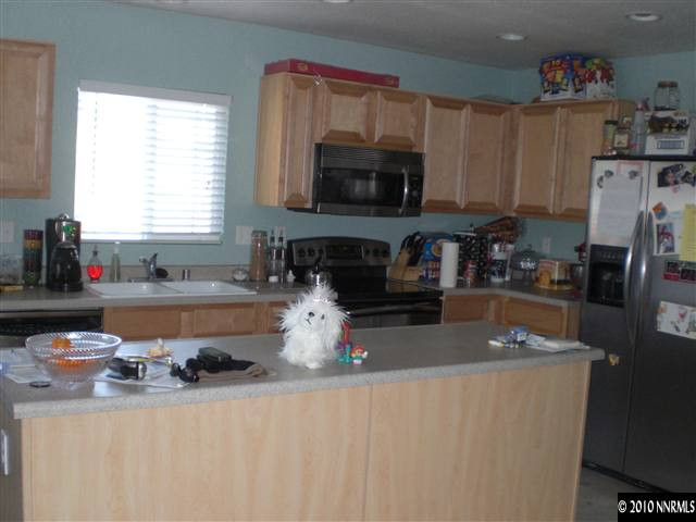 7764 Corso Street Reno, NV 89506 - Photo 3 of 7 a kitchen with stainless steel appliances granite countertop a sink a stove a refrigerator a sink a counter space and cabinets