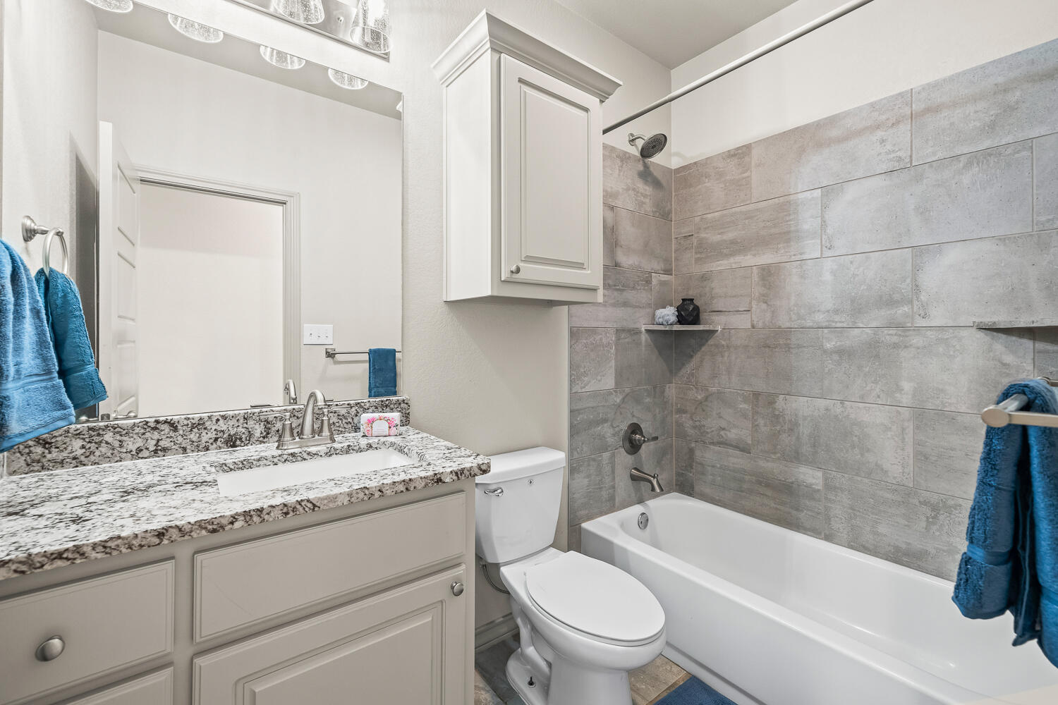 7613 61st Street Lubbock, TX 79407 - Photo 32 of 37 a bathroom with a granite countertop sink a toilet and bathtub