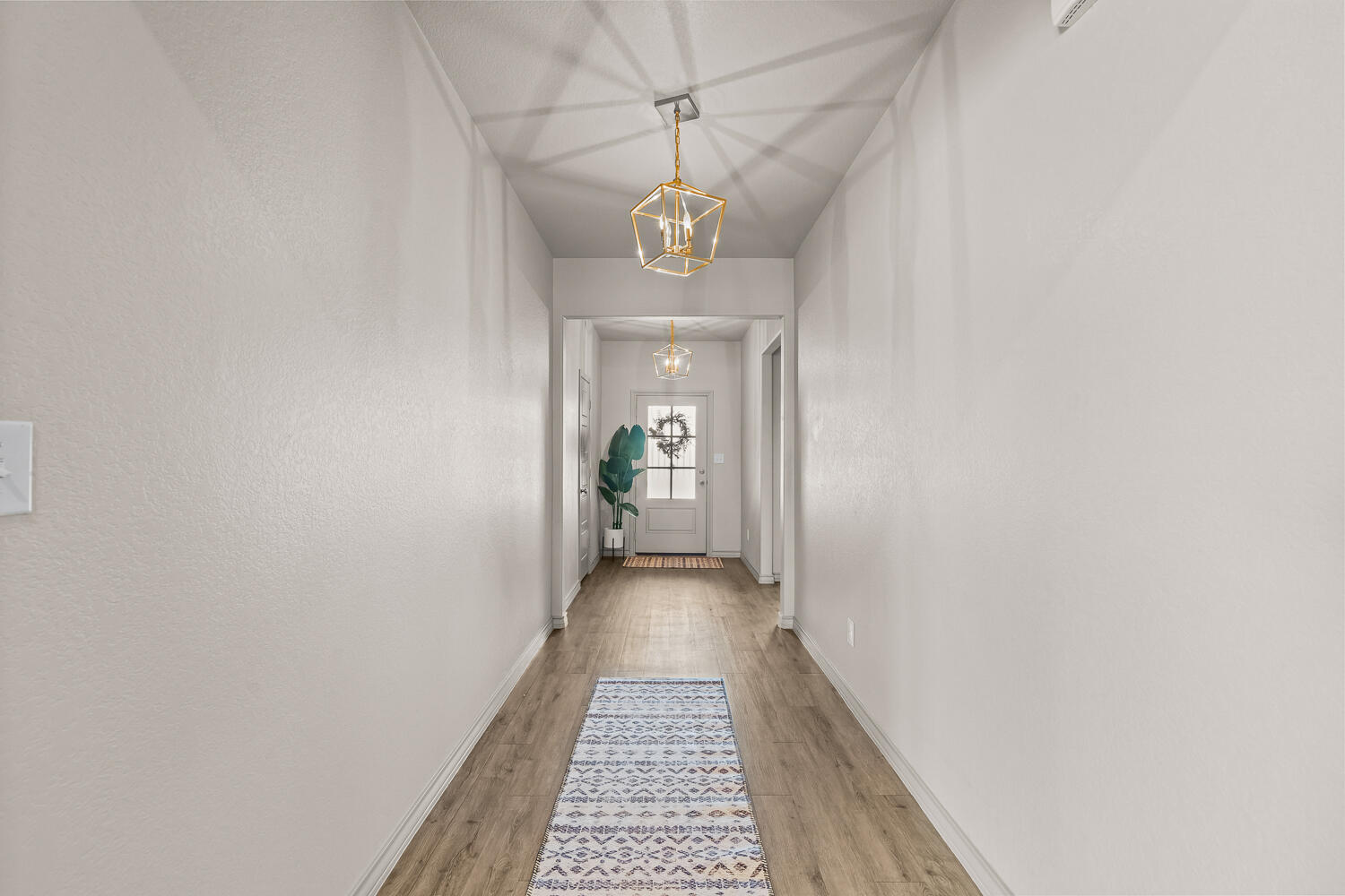 7613 61st Street Lubbock, TX 79407 - Photo 4 of 37 a view of a hallway with wooden floor and a chandelier