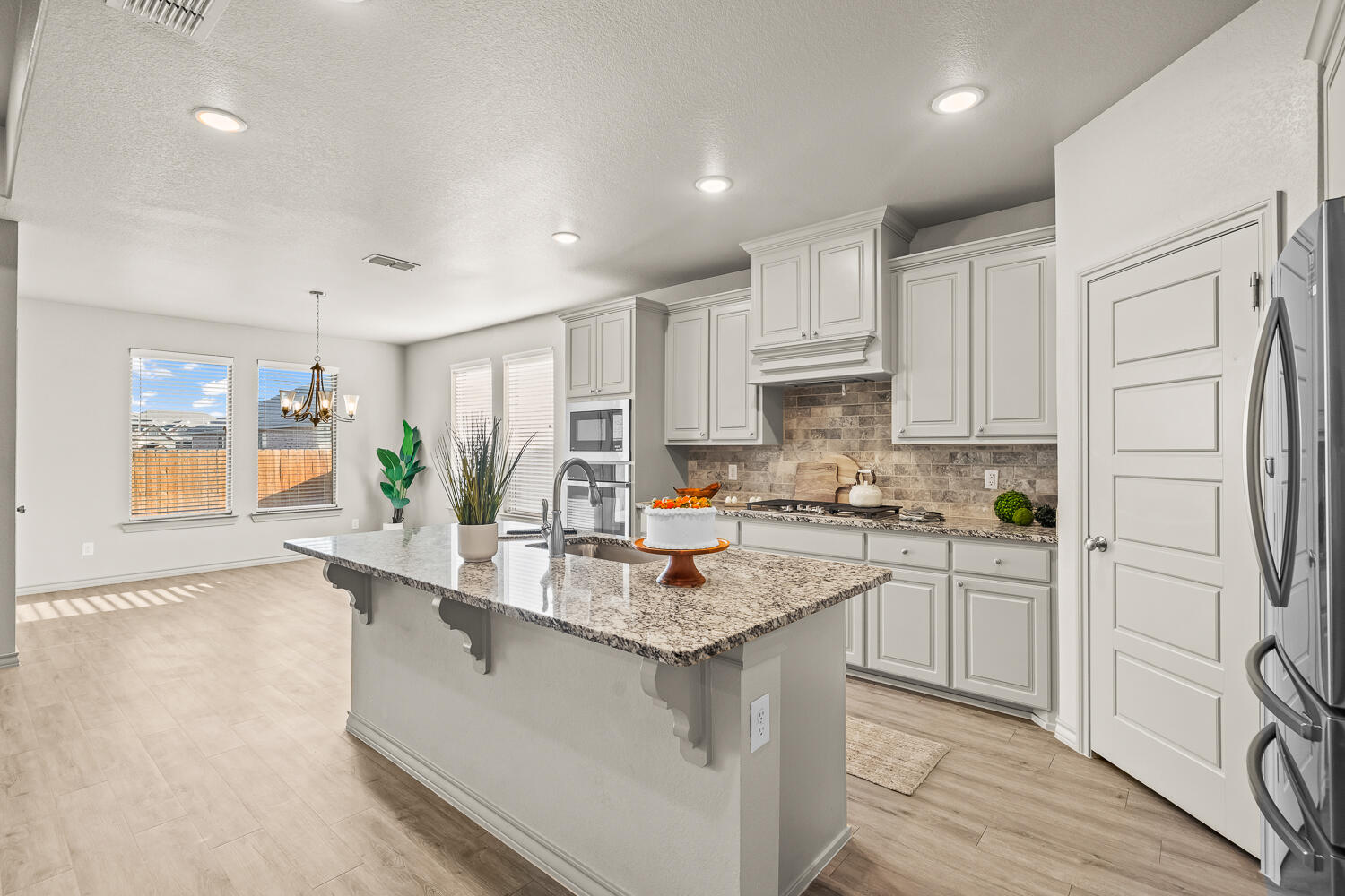 7613 61st Street Lubbock, TX 79407 - Photo 7 of 37 a kitchen with stainless steel appliances granite countertop a refrigerator a sink dishwasher and white cabinets with wooden floor
